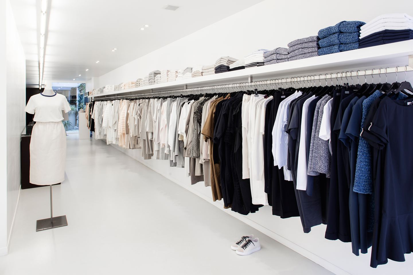 Blik door de winkel van Pure in Kortrijk: een wit interieur met een lang rek kleding aan de rechterkant