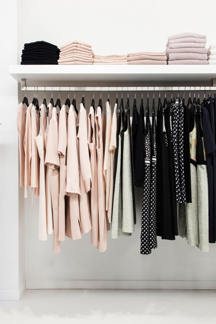 Rek met kleding in poeder en zwart onder een plank met gevouwen truien