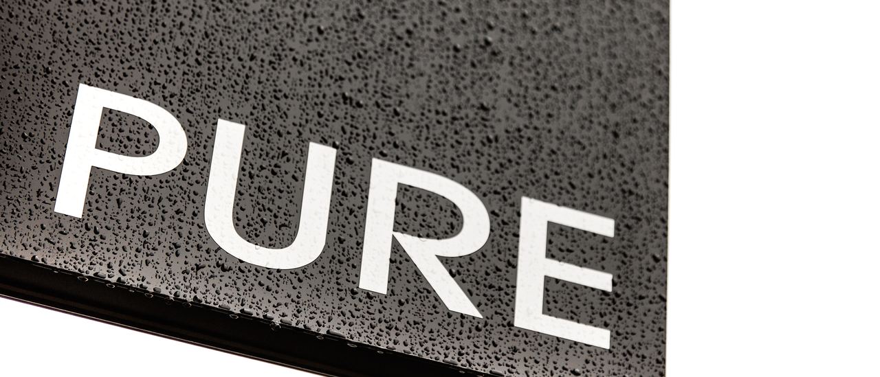 Het bord van Pure aan de gevel: witte letters in donkere natuursteen